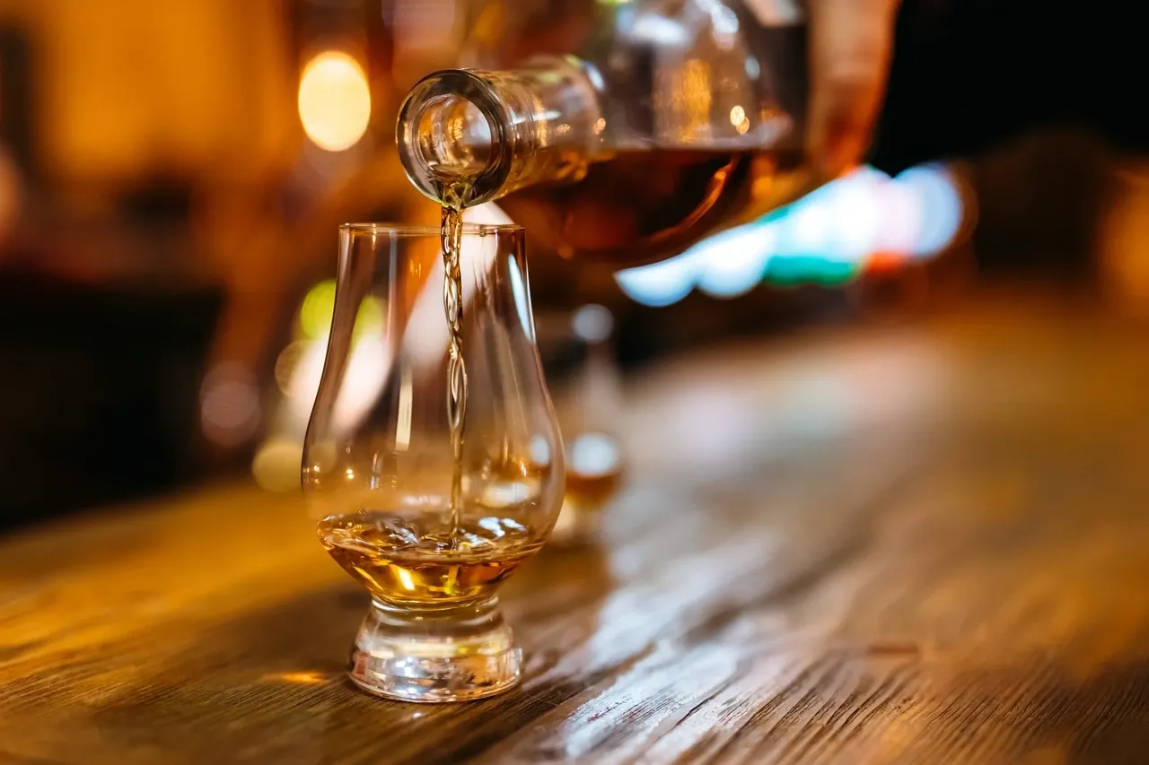 rs=w_1280,h_853 Pouring whiskey into a glass on table.